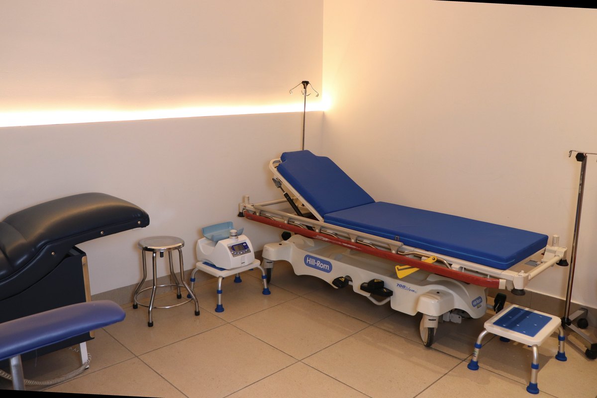 Sala de donación con camilla reclinable, sillón de flebotomía y banco de altura.